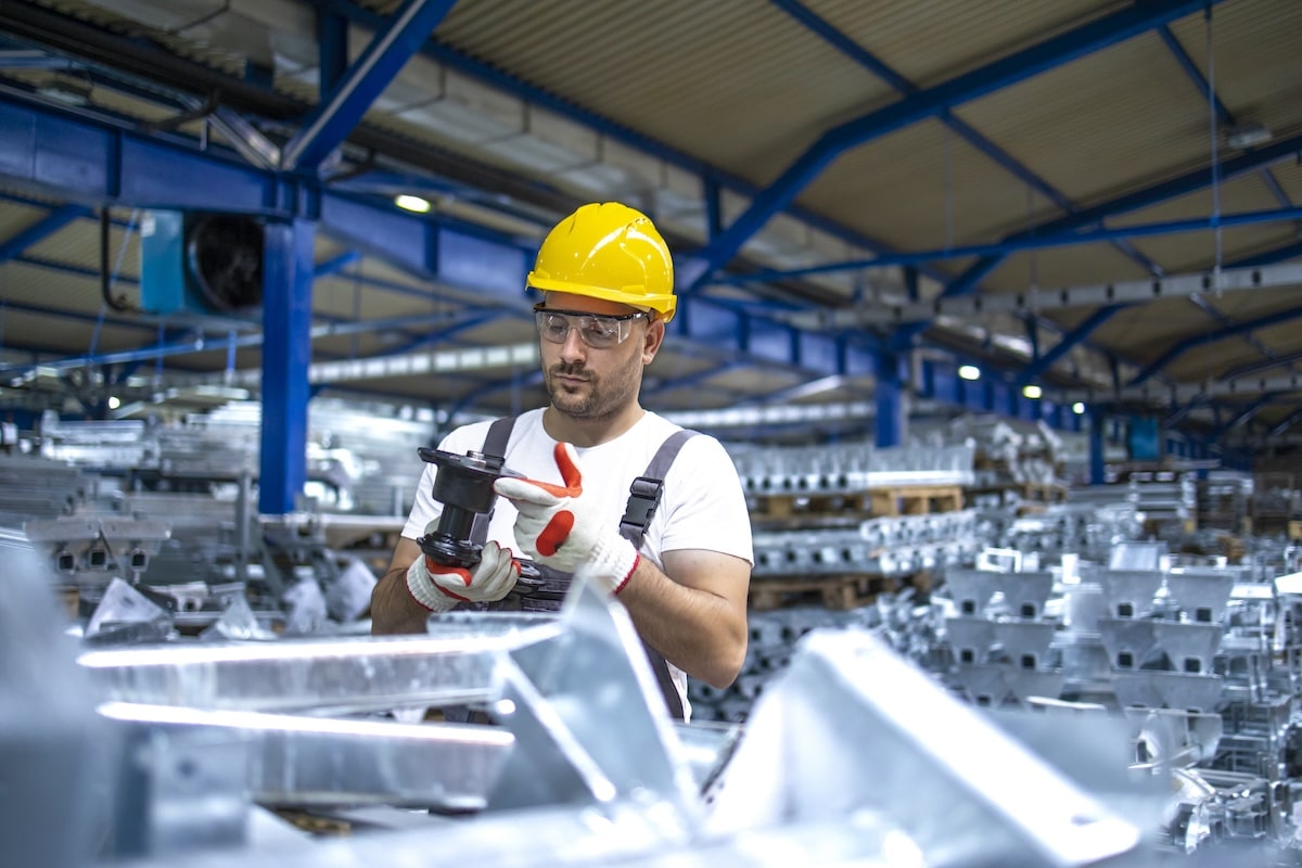 Operaio di fabbrica che lavora in un capannone di produzione industriale