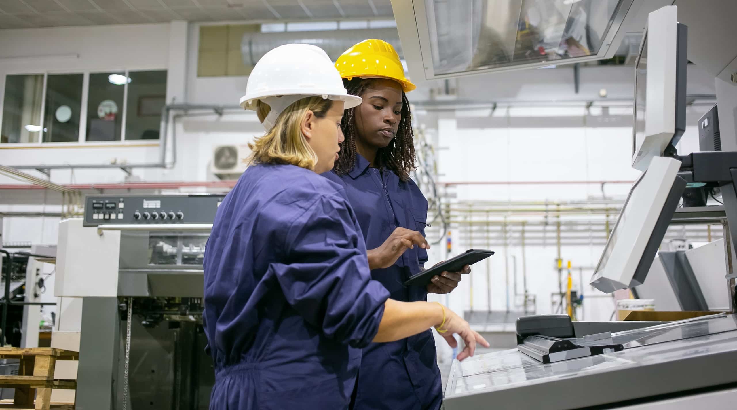 Donna impiegata nell'industria che insegna a un collega a manovrare un macchinario