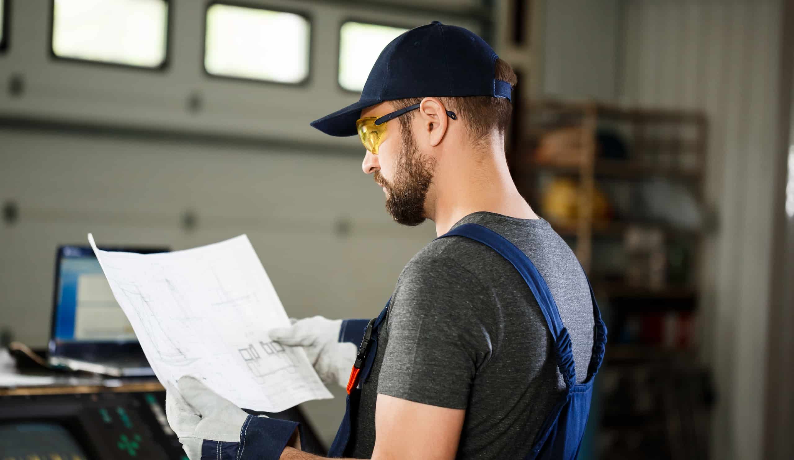 Operaio di fabbrica che guarda un progetto su carta