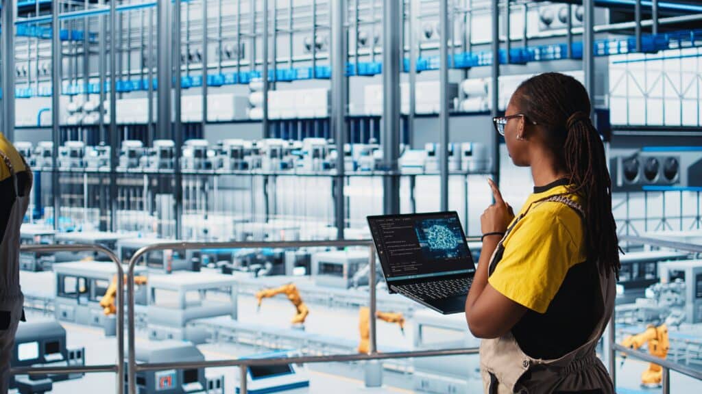 Engineer in smart factory using augmented reality to collect data on laptop