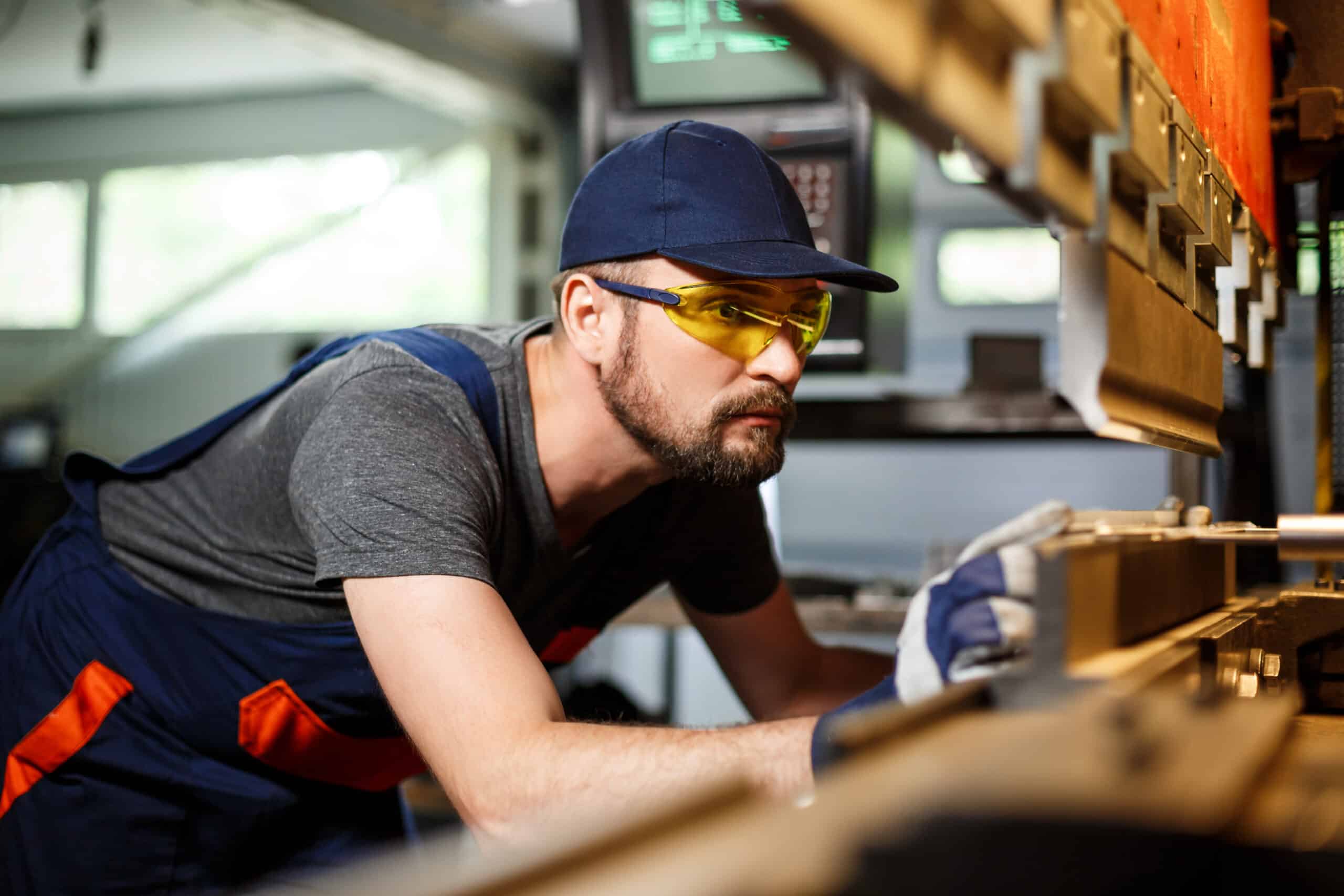 Portrait of worker near metalworking machine, steel factory background.